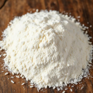 A mound of flour rests on a rustic wooden table, showcasing its fine texture and natural color.