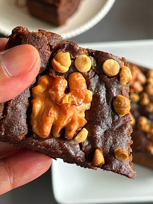 Close-up of a fudgy chocolate brownie topped with walnuts and hazelnuts.