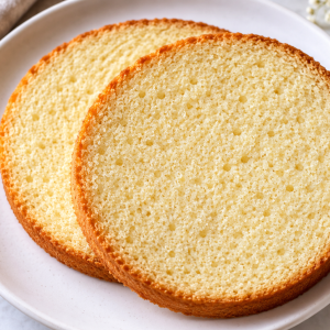 Two slices of vanilla sponge cake showing a soft, even crumb